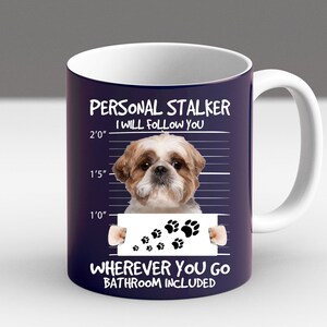 May include: A white ceramic mug with a blue background and a white border. The mug features a cartoon image of a Shih Tzu dog with the text "PERSONAL STALKER I WILL FOLLOW YOU" and "WHEREVER YOU GO BATHROOM INCLUDED".