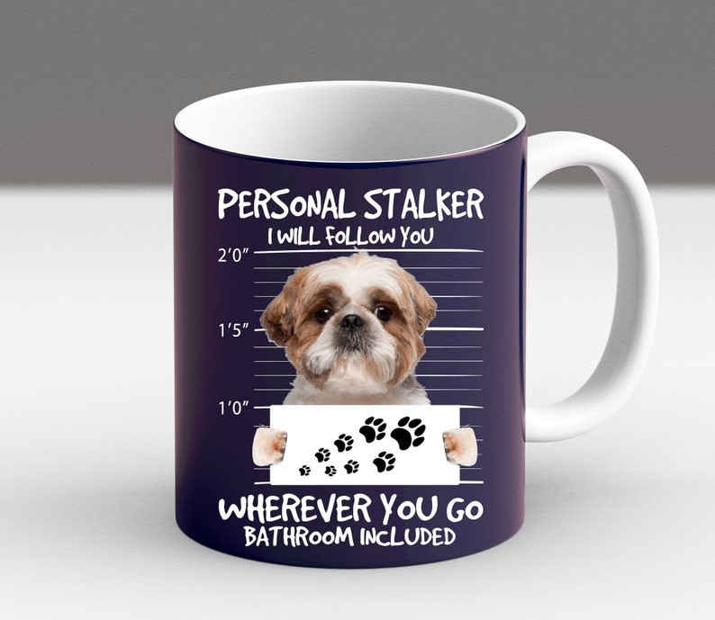May include: A white ceramic mug with a blue background and a white border. The mug features a cartoon image of a Shih Tzu dog with the text "PERSONAL STALKER I WILL FOLLOW YOU" and "WHEREVER YOU GO BATHROOM INCLUDED".