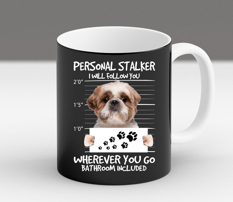 May include: Black ceramic mug with a white interior and handle. The mug features a white graphic of a Shih Tzu dog with the text "PERSONAL STALKER I WILL FOLLOW YOU WHEREVER YOU GO BATHROOM INCLUDED".