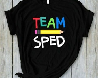 Könnte beinhalten: Schwarzes T-Shirt mit dem Text "TEAM" in Regenbogenfarben und "SPED" in Weiß mit einem gelben Bleistift darunter.