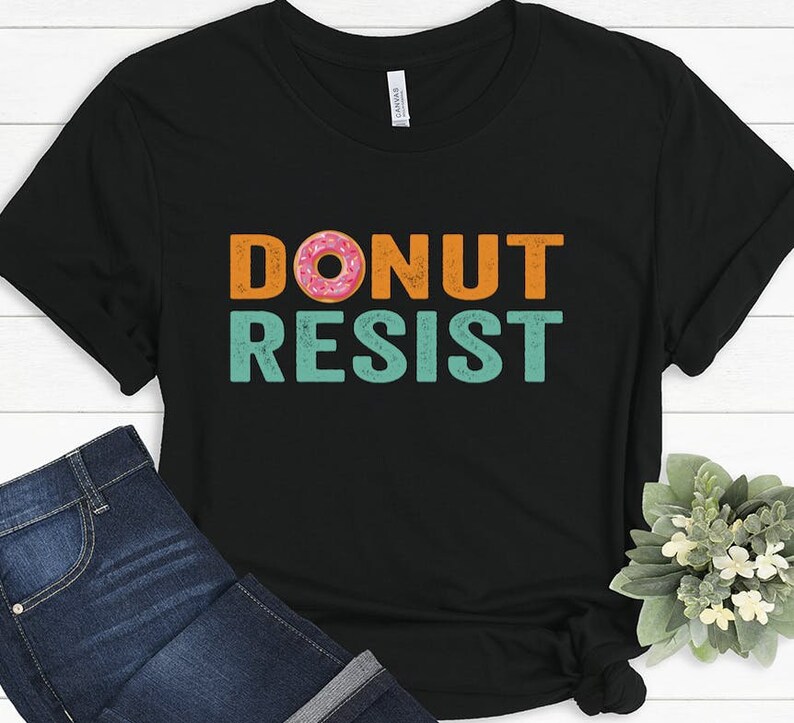 Pode incluir: Camiseta preta com um gr&aacute;fico de estilo vintage que diz "Donut Resist" com um gr&aacute;fico de donut rosa e laranja.