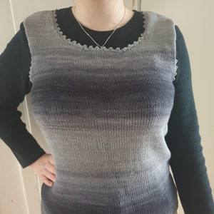 Könnte beinhalten: Eine graue und schwarze Ombre-Strickweste ohne Ärmel mit einem gewellten Ausschnitt.