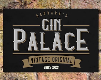 May include: Black sign with gold lettering that reads "Barbara's Gin Palace Vintage Original Since 2021".