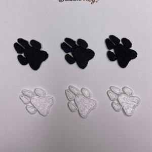 May include: Six paw print iron-on patches, three black and three white. The patches are in the shape of a paw print with four toes and a heel.