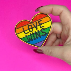 May include: A rainbow heart-shaped patch with the text "LOVE WINS" in black embroidery.