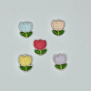 May include: Five embroidered iron-on patches in the shape of tulips. The tulips are in various colors: light blue, light pink, yellow, red, and purple.