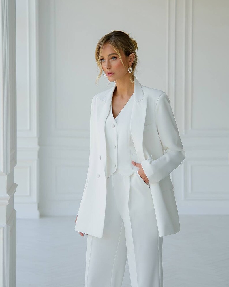 Puede incluir: Un traje de pantal&oacute;n blanco con chaqueta, chaleco y pantal&oacute;n. La chaqueta tiene cierre de doble botonadura y cuello en V. El chaleco tiene cuello en V y cierre de bot&oacute;n. El pantal&oacute;n tiene pierna recta.