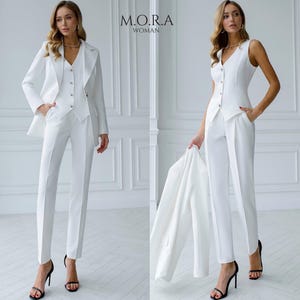 Puede incluir: Un traje de pantalón blanco con chaqueta, chaleco y pantalón. El traje está entallado y tiene un estilo moderno. La modelo lleva tacones negros.