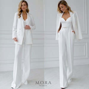 Puede incluir: Un conjunto de blazer blanco y pantalón de pierna ancha. El blazer tiene cierre de doble botonadura y el pantalón tiene cintura alta.