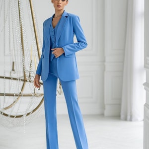 Puede incluir: Un traje de pantal&oacute;n azul claro con una chaqueta y pantalones a juego. La chaqueta tiene un cierre de un bot&oacute;n y una solapa de muesca. Los pantalones tienen una pierna recta.