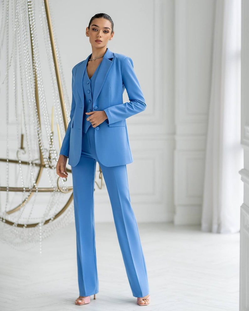 Puede incluir: Un traje de pantal&oacute;n azul claro con una chaqueta y pantalones a juego. La chaqueta tiene un cierre de un bot&oacute;n y una solapa de muesca. Los pantalones tienen una pierna recta.