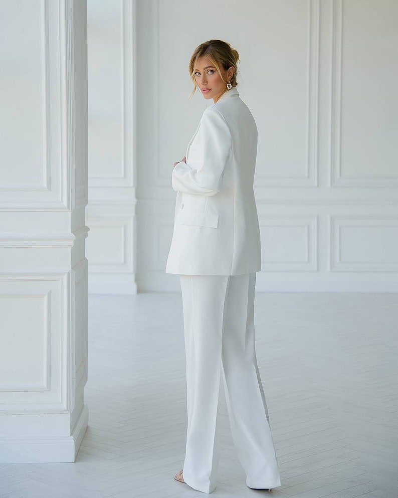 Puede incluir: Una chaqueta blanca y pantalones a juego. La chaqueta tiene cierre de doble botonadura y solapa de muesca. Los pantalones tienen pierna ancha.