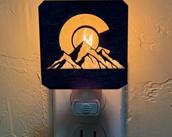 Luz nocturna con sensor de luz y escena de montaña con bandera de Colorado