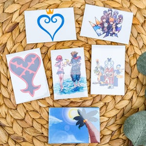 May include: Five different Kingdom Hearts themed magnets. The magnets feature various characters and symbols from the video game series. The magnets are all rectangular and have a white background.