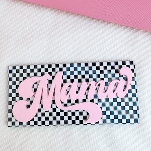 Pu&ograve; includere: Un cartello rosa "Mama" con un font retr&ograve; su uno sfondo a scacchi bianco e nero.