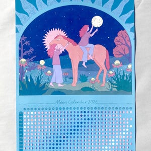 Op de afbeelding: Maankalender 2026 met een illustratie van twee figuren en een paard die naar de maan reiken. De kalender heeft een blauwe achtergrond met een zonontwerp en een maancycluskaart. De tekst "Moon Calendar 2026" is zichtbaar. Afmetingen in cm.