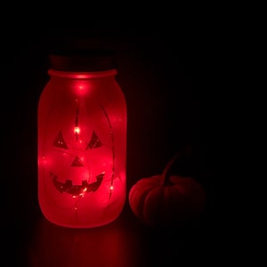 Jack-o-Lantern Etched Fairy Light Mason Jar Lantern. Halloween decoration for outside, parties, gifts, holidays. Orange battery fairy lights