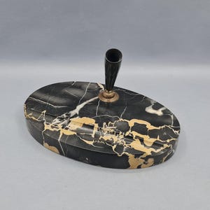 May include: An oval pen holder in black marble with gold veining. A black pen holder with a gold base is attached to the top. This vintage desk accessory is a stylish addition to any workspace.