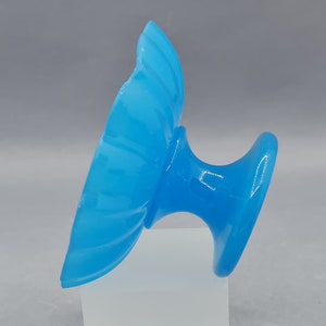 Può includere: Una ciotola in vetro blu con piedistallo e design scanalato. La ciotola è su una superficie bianca.