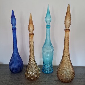 Pode incluir: Quatro garrafas de vidro vintage com diferentes texturas e cores. As garrafas s&atilde;o azuis, marrons e transparentes. Elas t&ecirc;m um design retro &uacute;nico.