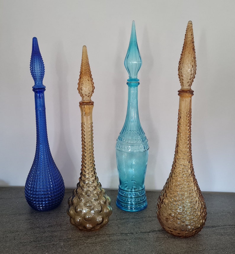 Pode incluir: Quatro garrafas de vidro vintage com diferentes texturas e cores. As garrafas s&atilde;o azuis, marrons e transparentes. Elas t&ecirc;m um design retro &uacute;nico.