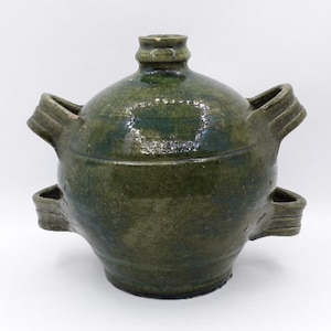 May include: A green ceramic pitcher with four handles. The pitcher has a rounded body and a slightly flared lip.