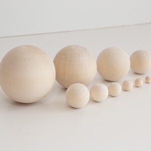 May include: A set of ten wooden spheres in various sizes, ranging from small to large. The spheres are all a natural wood color and are arranged in a line from smallest to largest.