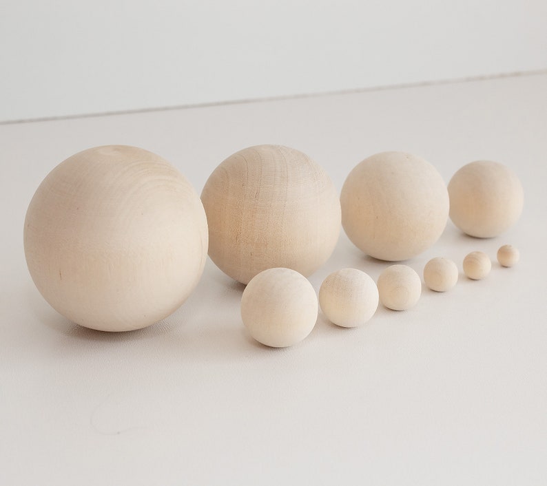 May include: A set of ten wooden spheres in various sizes, ranging from small to large. The spheres are all a natural wood color and are arranged in a line from smallest to largest.