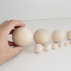 May include: A set of ten wooden balls of varying sizes, arranged in order from largest to smallest. The balls are a natural wood color and have a smooth, polished finish.