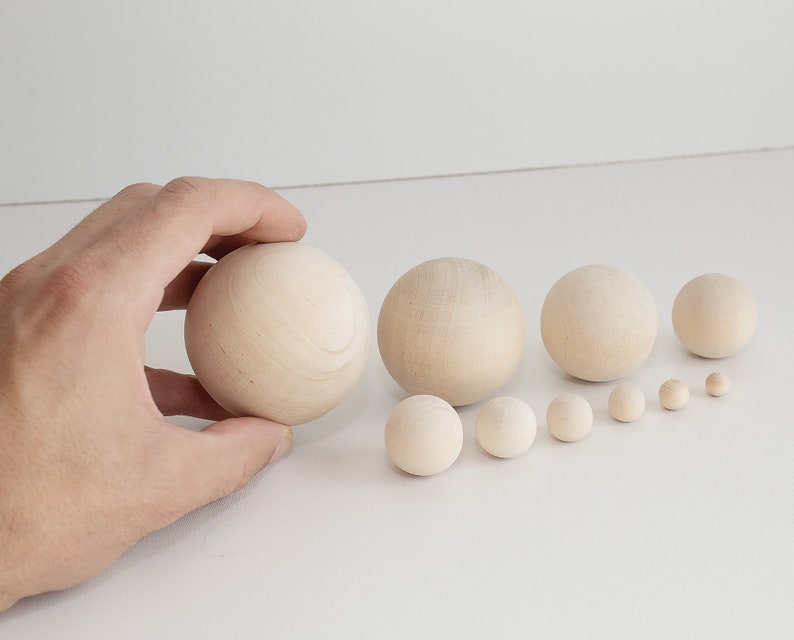 May include: A set of ten wooden balls of varying sizes, arranged in order from largest to smallest. The balls are a natural wood color and have a smooth, polished finish.