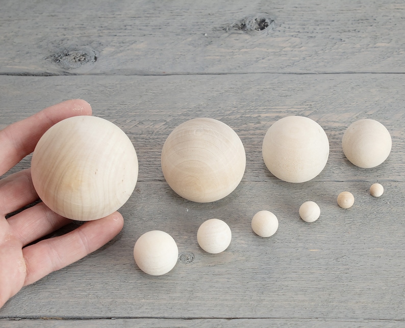 May include: A set of ten wooden balls in various sizes, ranging from small to large. The balls are all natural wood color and are arranged in a line from largest to smallest.