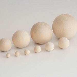 May include: A set of ten wooden spheres of varying sizes, ranging from small to large. The spheres are all a natural wood color and are arranged in a line from smallest to largest.