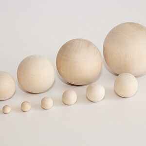 May include: A set of ten wooden spheres of varying sizes, ranging from small to large, arranged in a row on a white surface.