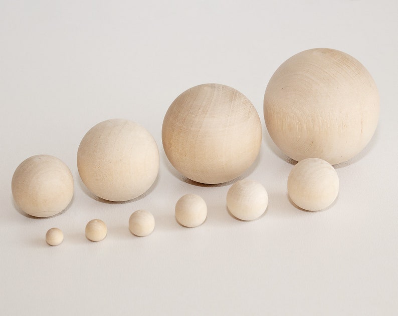 May include: A set of ten wooden spheres of varying sizes, ranging from small to large, arranged in a row on a white surface.