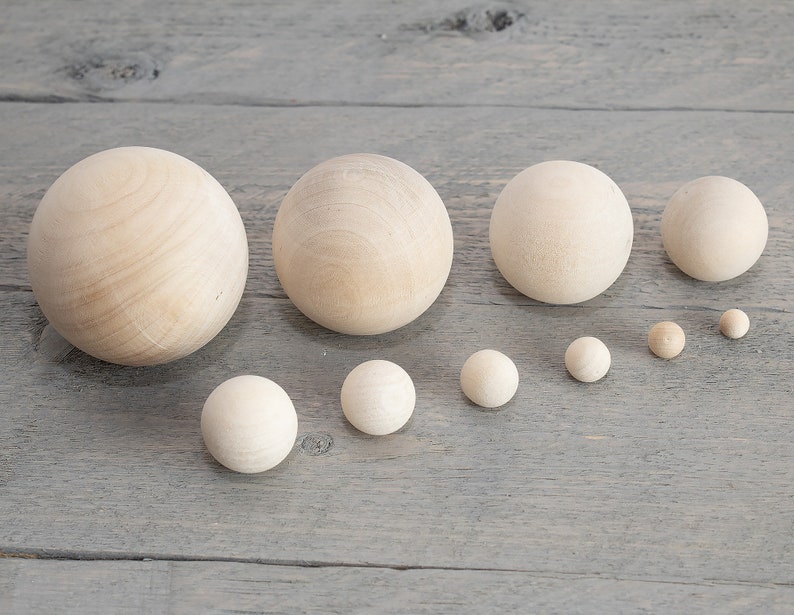 May include: A set of ten wooden balls of varying sizes, ranging from small to large. The balls are all smooth and unpainted, with a natural wood color.