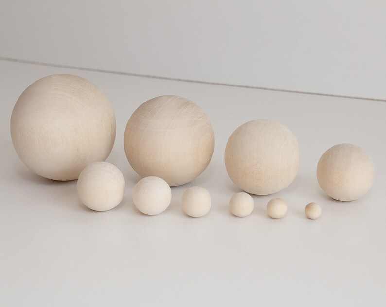 May include: A set of ten wooden balls in various sizes, ranging from small to large. The balls are all a natural wood color and are arranged in a line from largest to smallest.