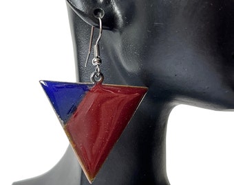 Könnte beinhalten: Ein Paar dreieckige Ohrringe mit zweifarbigem Design. Eine Hälfte ist tiefblau, die andere tiefrot. Die Ohrringe hängen an silberfarbenen Ohrhaken und präsentieren einen modernen, geometrischen Stil.