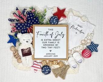 May include: A framed sign with the text "This Fourth of July is extra sweet our family is growing by two tiny feet! Arriving January 2025" surrounded by red, white, and blue baby items including a onesie, a teddy bear, a sonogram, and a star-shaped rattle.