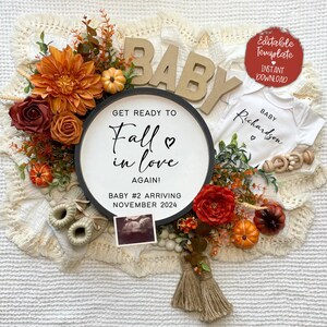 K&ouml;nnte beinhalten: Eine Baby-Ank&uuml;ndigung im Herbst-Thema mit einem schwarz-wei&szlig;en Schild, auf dem steht "Mach dich bereit, dich wieder zu verlieben! Baby Nr. 2 kommt im November 2024". Das Schild ist von Herbstlaub umgeben, darunter orange und rote Blumen, Bl&auml;tter und K&uuml;rbisse. Es gibt auch einen wei&szlig;en Strampler mit dem Text "Baby Richardson" darauf.