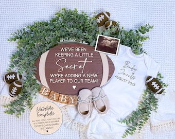 Pode incluir: Uma placa de madeira marrom com o texto "We've been keeping a little secret. We're adding a new player to our team!"  Um macacão branco com o texto "Baby Jacobs August 2025" e um anúncio de nascimento com tema de futebol.
