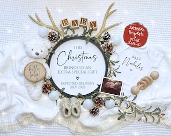 Könnte beinhalten: Eine Baby-Ankündigung zum Thema Weihnachten mit einer weißen Decke, einem Teddybär, einem Holzschild mit der Aufschrift "Dieses Weihnachten bringt uns ein ganz besonderes Geschenk. Erwarteter Geburtstermin Juli 2025", einem Baby-Strampler mit der Aufschrift "Baby Nicholas", einer Holzrassel und einem Ultraschallbild.