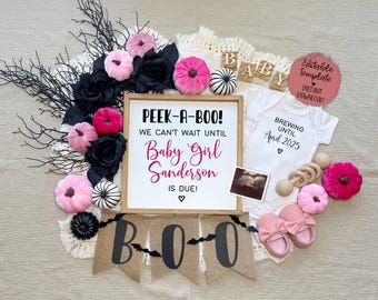 May include: A Halloween-themed baby announcement with a sign that reads "Peek-a-Boo! We can't wait until Baby Girl Sanderson is due!"  The sign is surrounded by pink and black pumpkins, black roses, and a banner that reads "BOO".