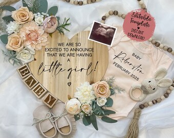 May include: A wooden heart-shaped sign with the text "We are so excited to announce that we are having a little girl!"  A baby onesie with the text "Baby Robertson February 2025" is next to the sign.  The sign is decorated with flowers and a baby's shoes.