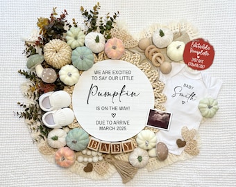 Könnte beinhalten: Ein rundes Schild aus weißem Holz mit dem Text "We are excited to say our little Pumpkin is on the way! Due to arrive March 2025". Das Schild ist von Herbstdekorationen umgeben, darunter Kürbisse, Kürbisse und Blätter. Es gibt auch einen weißen Strampler mit dem Text "Baby Smith" darauf.