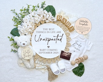 May include: A white wooden sign with the text "The best things in life are unexpected" and a heart symbol. Below the text is "Baby coming September 2025". There is a white baby onesie with the text "Baby Mason" and a heart symbol. There is a white teddy bear holding a round wooden sign with the text "Hello Baby!" There is a white ultrasound image, a wooden rattle, and white flowers.