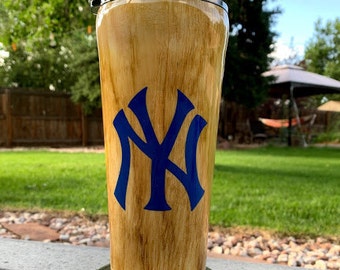 May include: A stainless steel tumbler with a wood grain design and a blue New York Yankees logo.