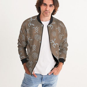 May include: A brown bomber jacket with a blue and white pattern of stylized animal and geometric shapes. The jacket has a zipper closure and black ribbed cuffs and collar.