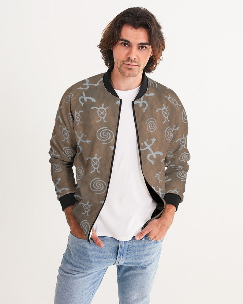 May include: A brown bomber jacket with a blue and white pattern of stylized animal and geometric shapes. The jacket has a zipper closure and black ribbed cuffs and collar.