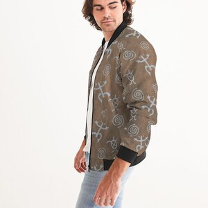 May include: A brown bomber jacket with a blue and brown pattern of stylized animal and spiral designs. The jacket has a black zipper and black ribbed cuffs and waistband.