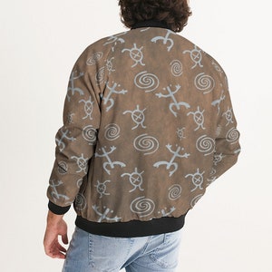 May include: A brown bomber jacket with a blue and white pattern of stylized turtles and spirals. The jacket has a black ribbed collar, cuffs, and waistband.